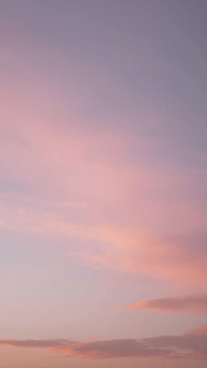 Vertical view of a soft gradient sunset sky filled with wispy pink and purple clouds