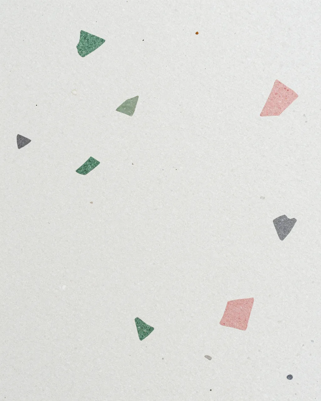 Close-up of a white terrazzo surface with scattered green, pink, and gray irregular stone chips