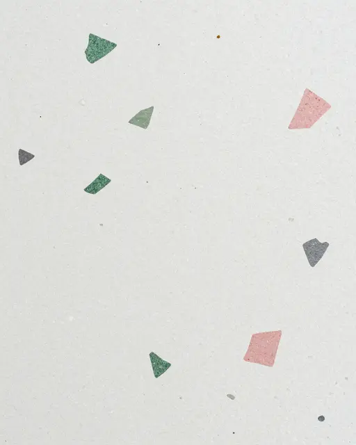 Close-up of a white terrazzo surface with scattered green, pink, and gray irregular stone chips