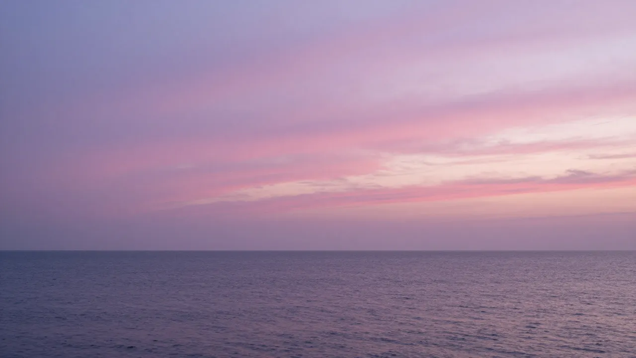 Pink and purple streaked twilight sky sits over a calm, gently rippled ocean horizon.