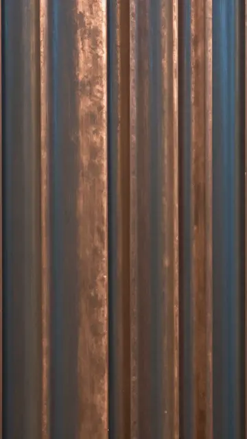Full frame close up of vertically ribbed copper sheet with bronze and blue chemical patina lit by soft light