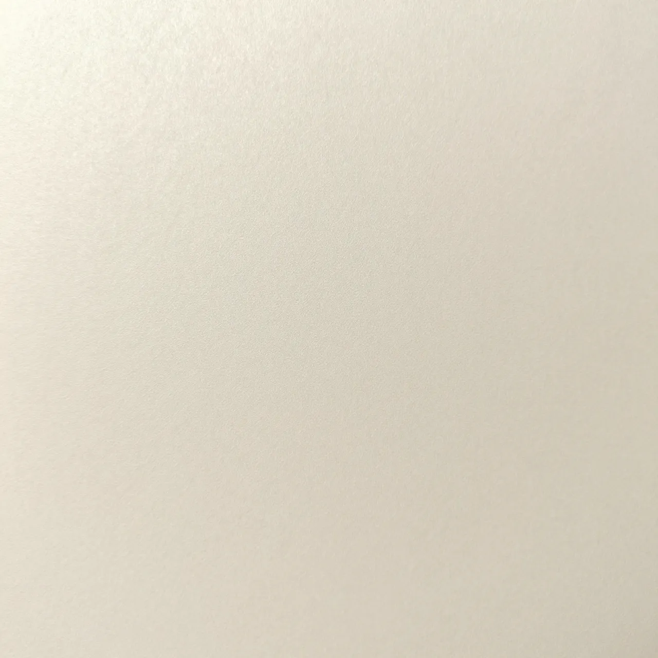 Full frame close-up of smooth pearlescent ivory paper with a soft subtle shimmer