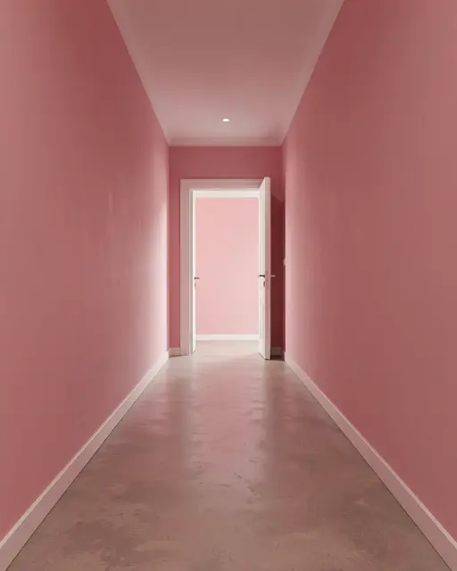 A long empty pink walled hallway leads to an open white door at the far end