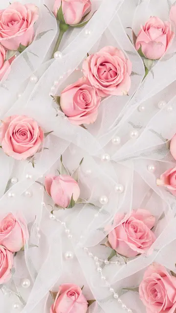 Soft pink rosebuds and scattered pearls arranged across draped sheer white tulle