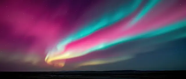 Vibrant pink and teal aurora ribbons arc across a starry dark night sky above a distant horizon