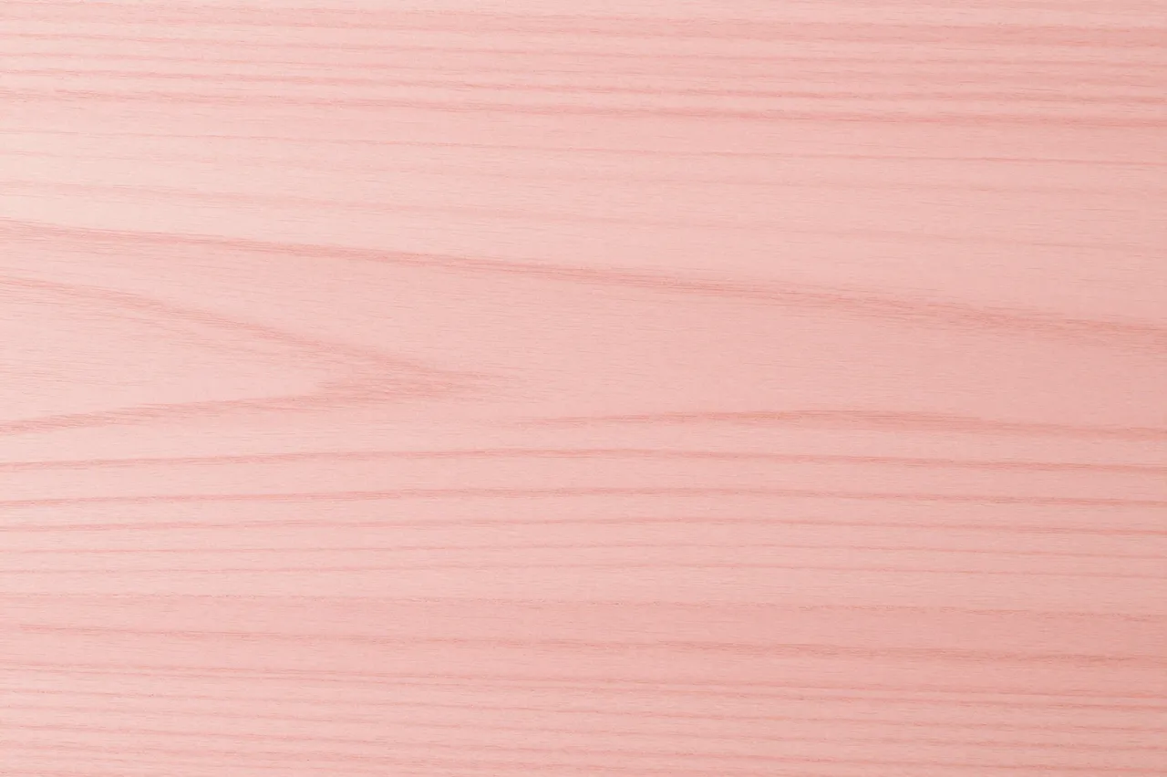 Full frame close-up of smooth pink toned beech wood with fine horizontal grain patterns under flat even light