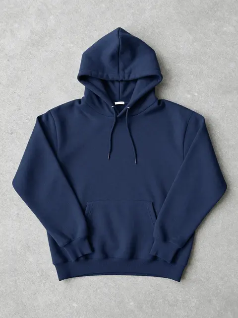 A flat-lay plain navy hoodie rests spread out on a smooth gray concrete surface.