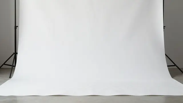 Empty seamless white photo studio backdrop mounted on black metal stands with a curved floor transition