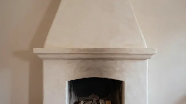 Smooth rounded plaster adobe fireplace set against warm neutral interior walls