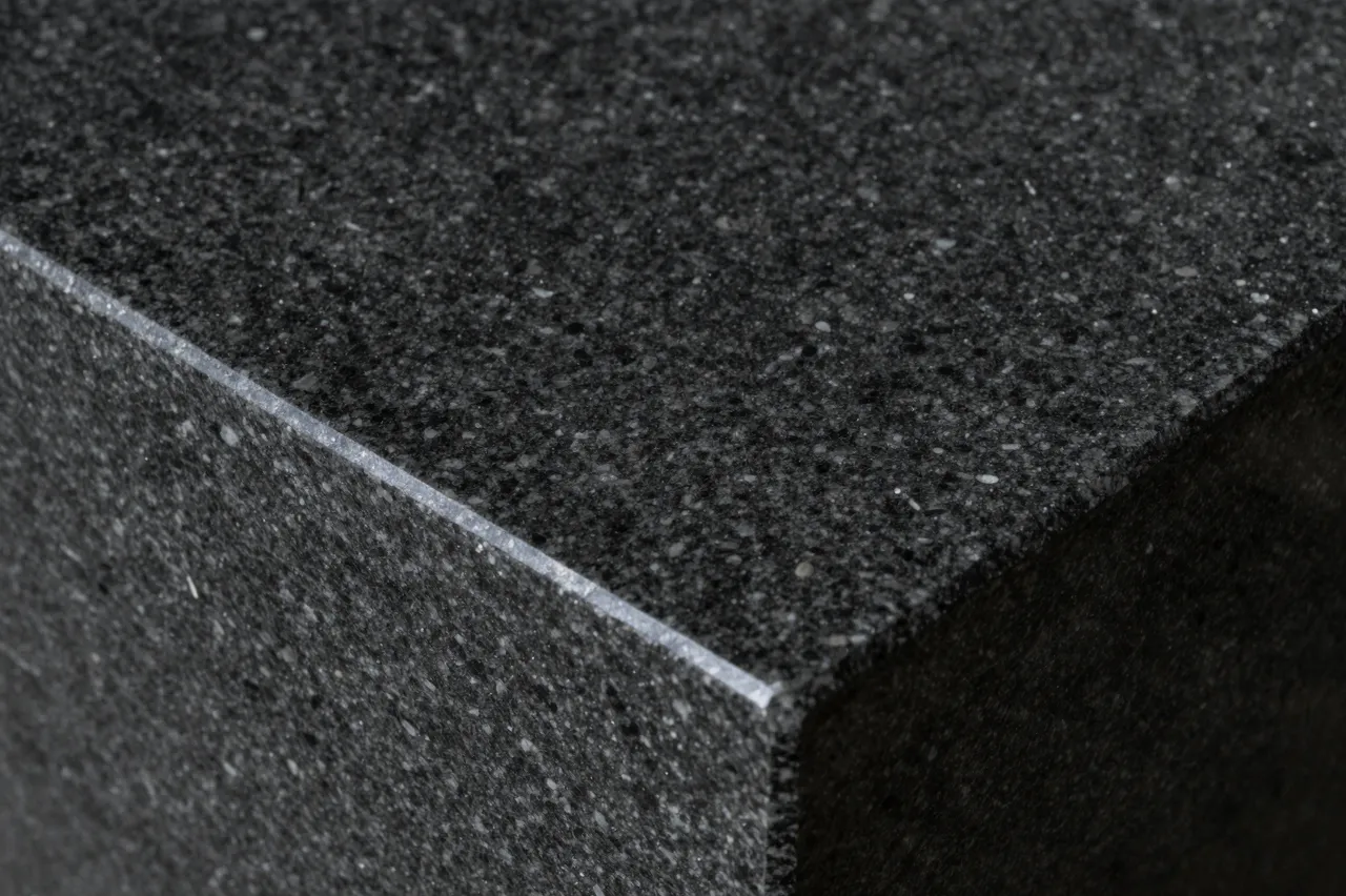 Close-up of the sharp corner edge of a polished black granite slab with fine sparkling flecks