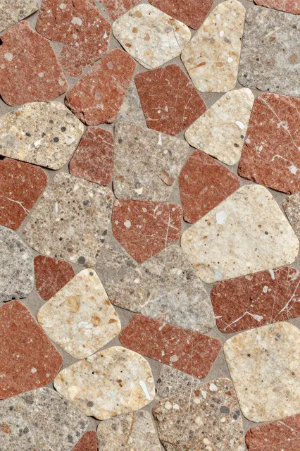 Full frame close-up of polished breccia with angular red, cream and gray stone fragments set in binding