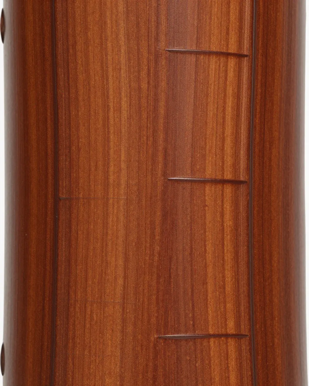 Full frame close-up of smooth polished cherry wood with carved horizontal linear details and warm brown grain