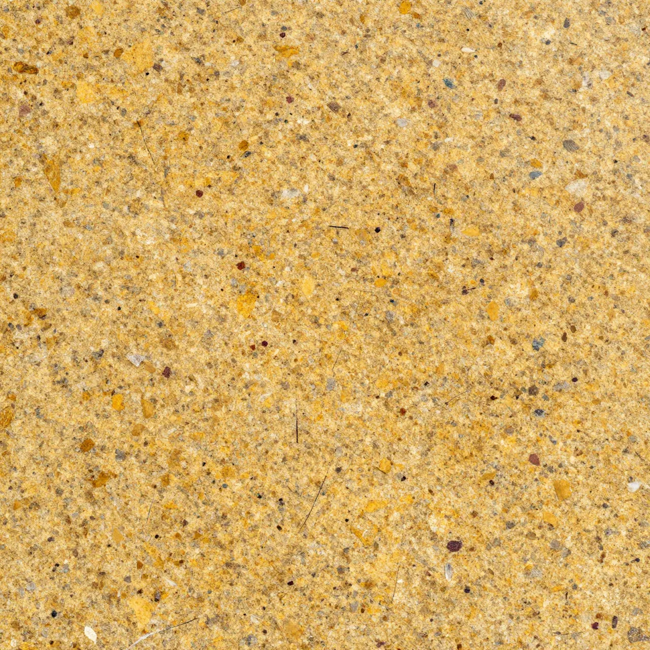 Full frame top view of a polished golden granite surface with scattered colored mineral flecks