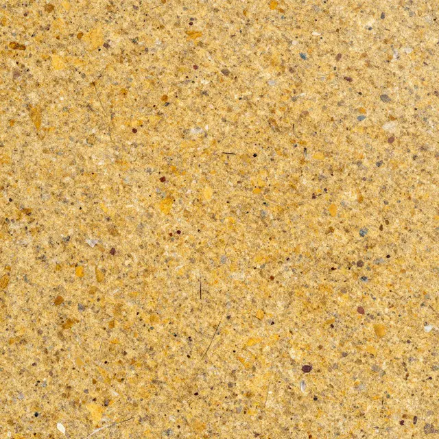 Full frame top view of a polished golden granite surface with scattered colored mineral flecks