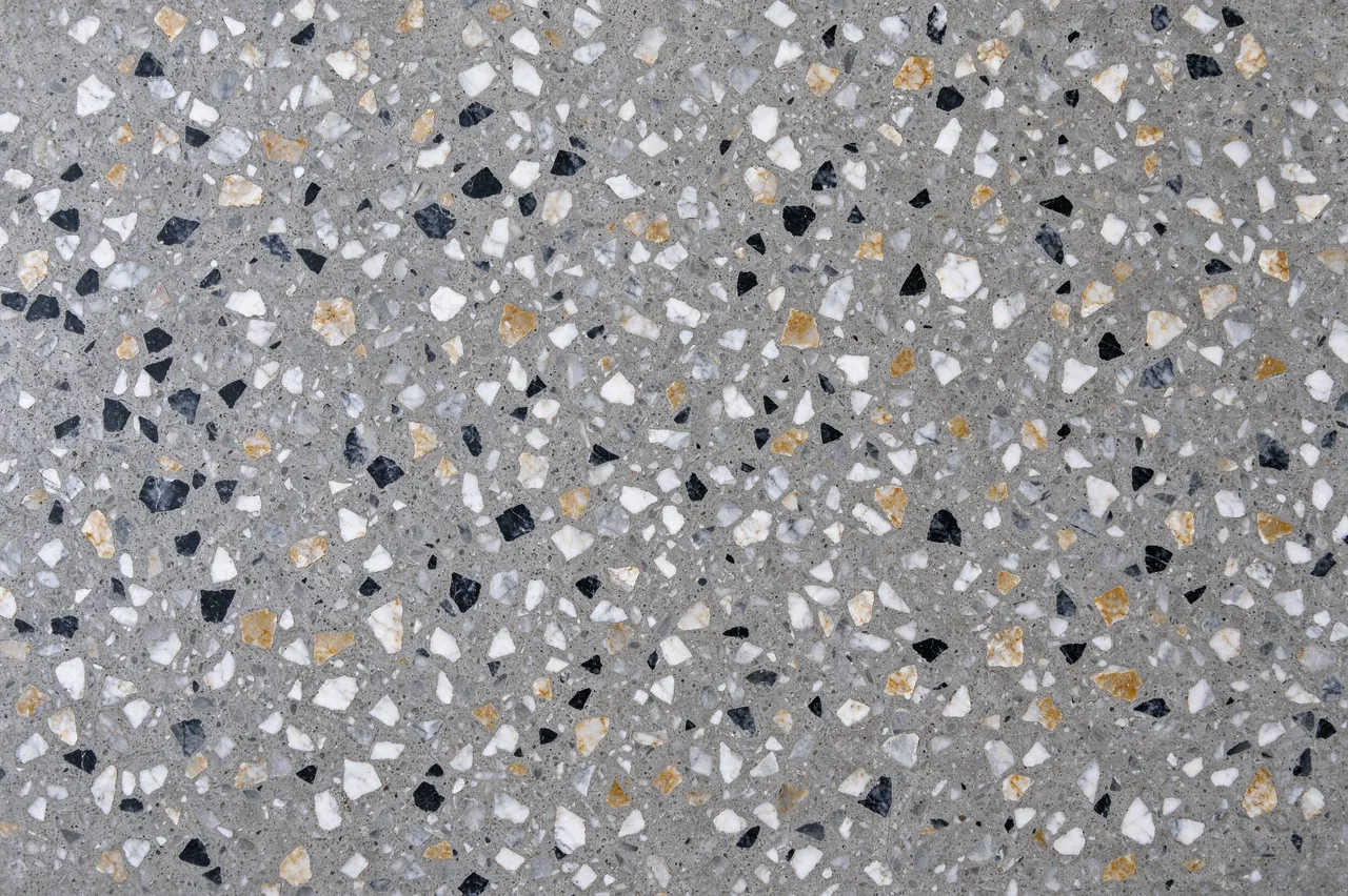 Top view of a full-frame polished terrazzo floor with gray cement, black, white and ochre marble chips