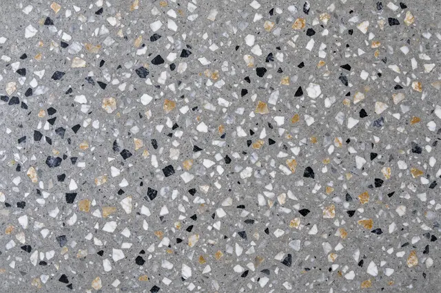 Top view of a full-frame polished terrazzo floor with gray cement, black, white and ochre marble chips