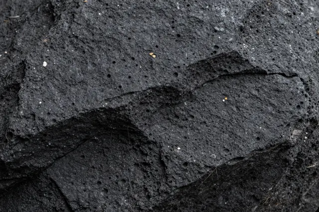 Close-up view of the rough, pitted surface of dark porous basalt rock