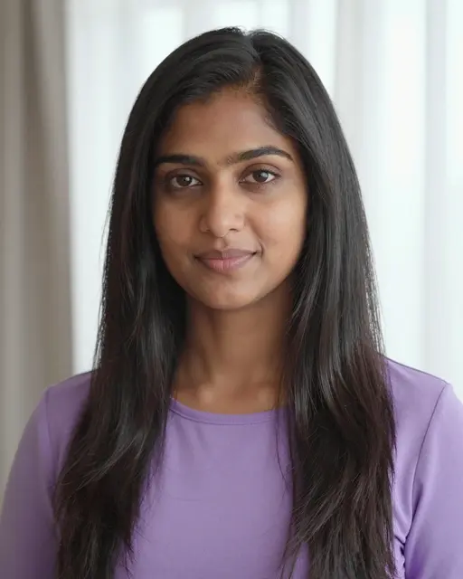 Soft window light falls on a South Asian woman in her thirties with long straight dark hair wearing a lilac top.