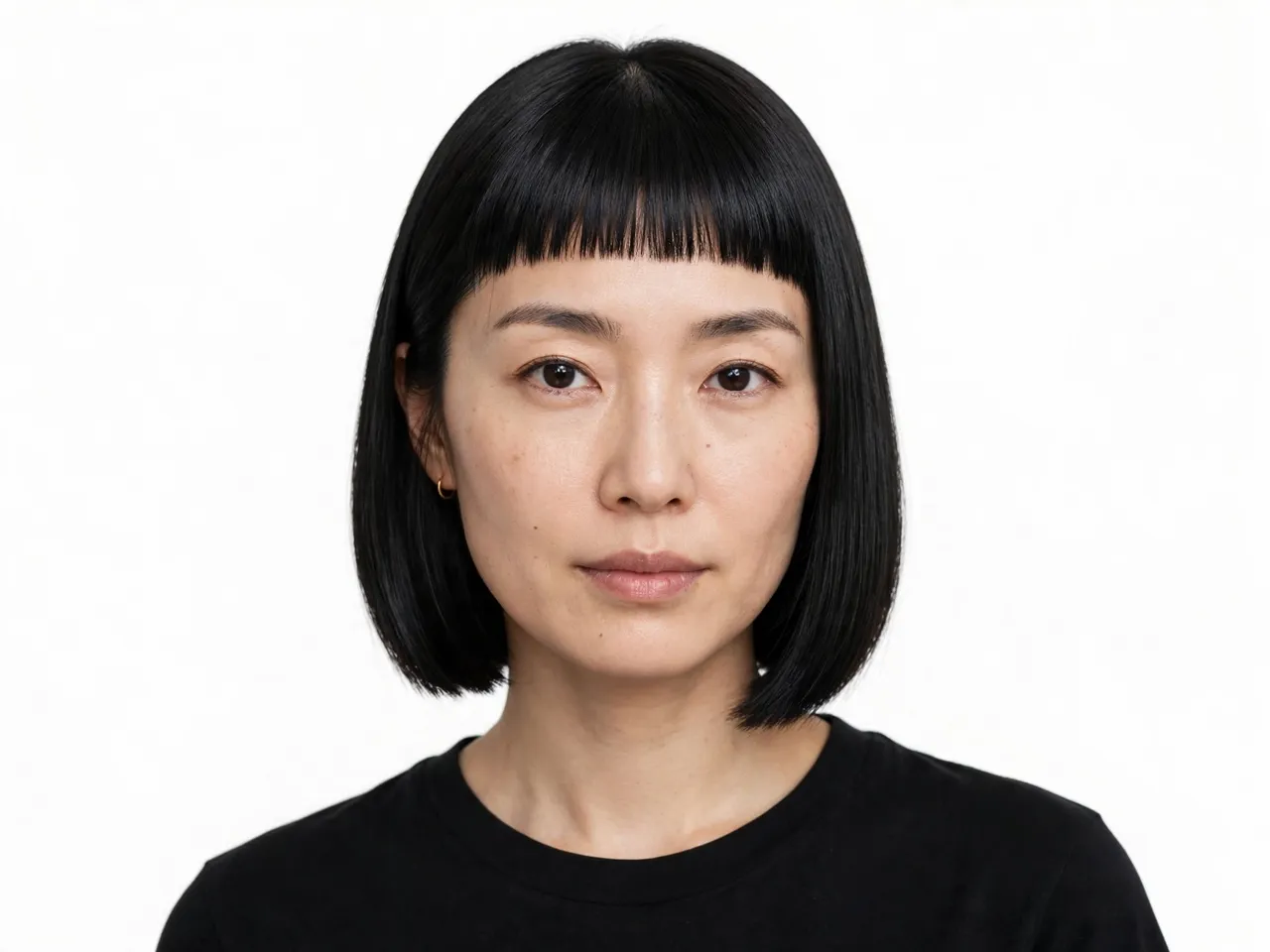 Headshot of a East Asian woman in her thirties with a sleek bob and micro bangs wearing a black top against a plain white