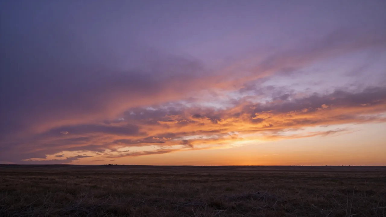 Purple and orange sunset clouds stretch above a wide flat grass prairie horizon