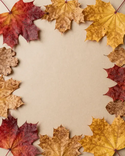 A top-down view of pressed fall maple leaves arranged in a border around empty kraft paper.
