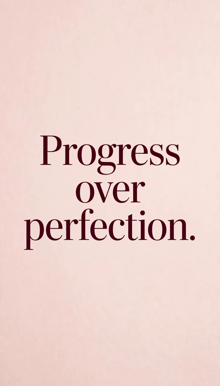 "Progress over perfection." displayed in deep burgundy serif type on a soft blush pink background, formatted as a phone