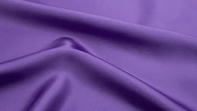 Close up of smooth deep purple silk fabric with soft gentle folds and natural ripples