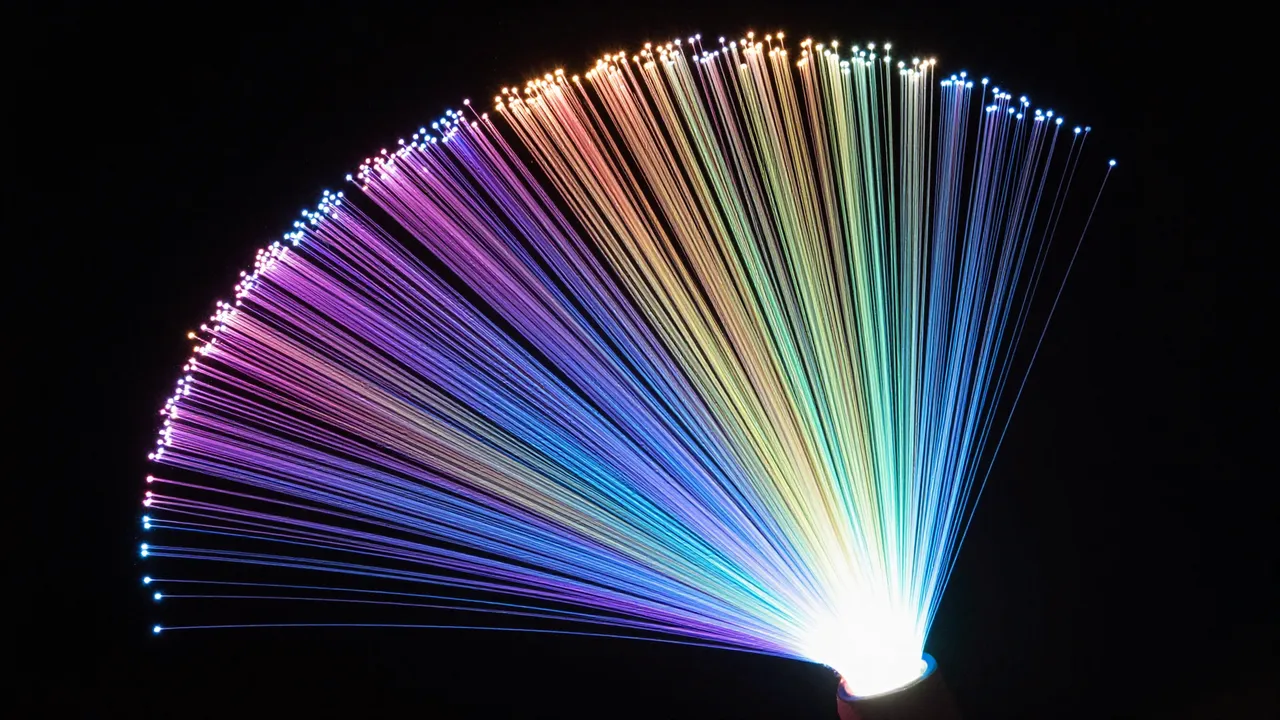 Fan-shaped array of glowing rainbow fiber optic strands spread against solid black