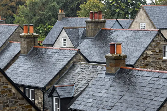 Wet slate rooftops and stone chimneys of old town houses during a light rain shower
