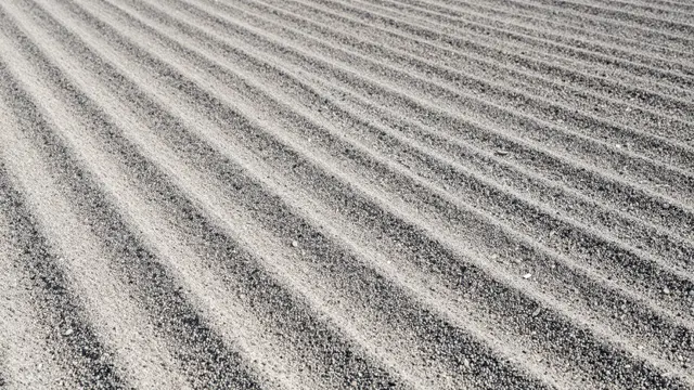 Top view of smooth parallel raked wave patterns across fine gravel under soft light