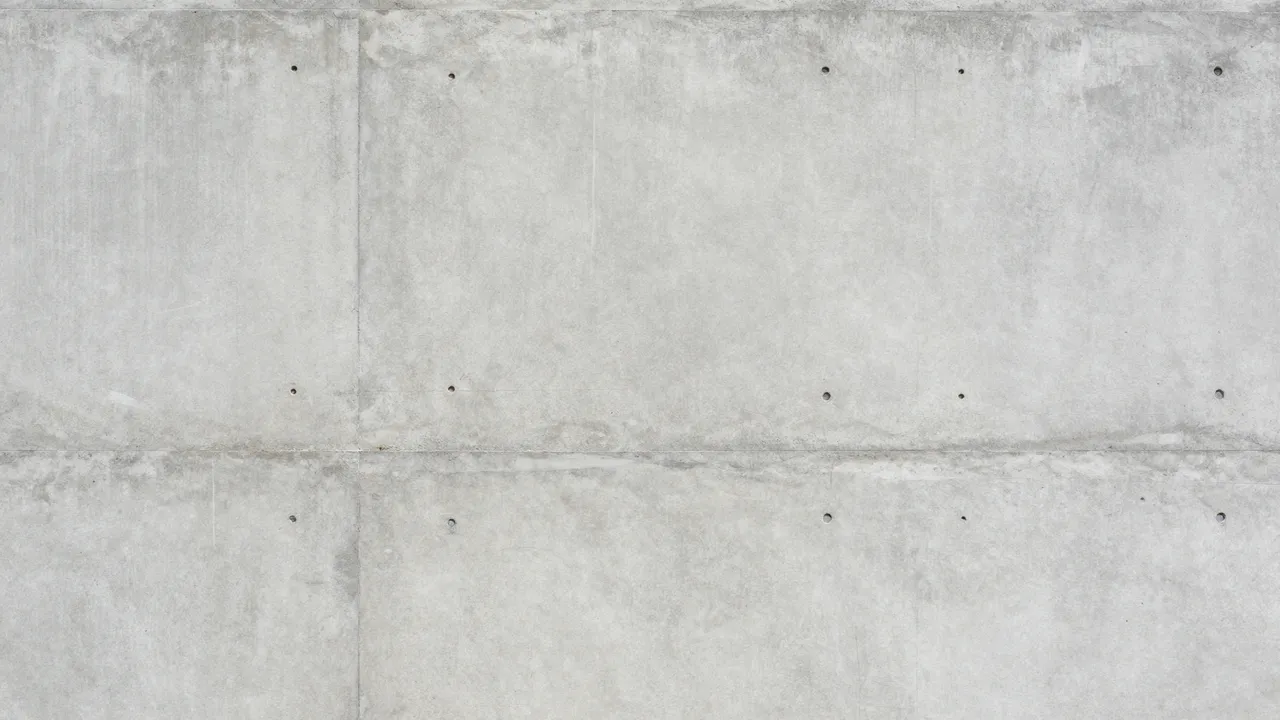 Full frame view of a raw gray concrete wall with formwork seams and evenly spaced tie holes