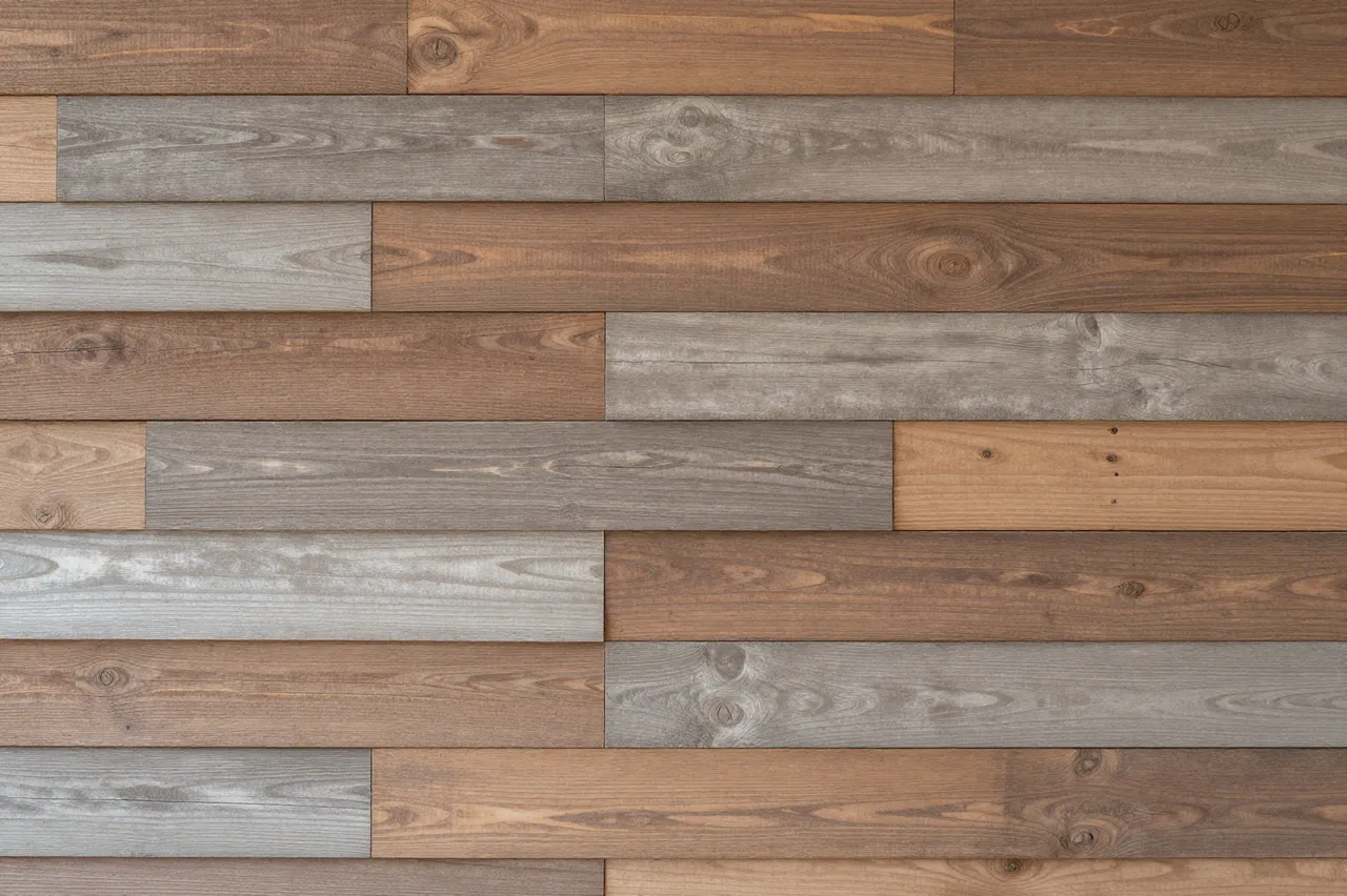Full frame close-up of staggered mixed-tone reclaimed wood wall planks with even soft lighting