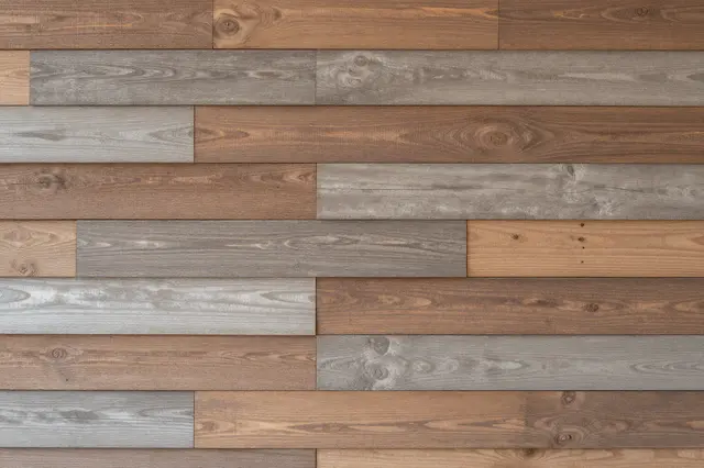 Full frame close-up of staggered mixed-tone reclaimed wood wall planks with even soft lighting