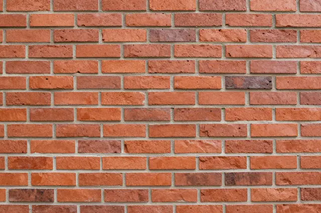 A close up view of a uniform red brick wall with light gray mortar joints