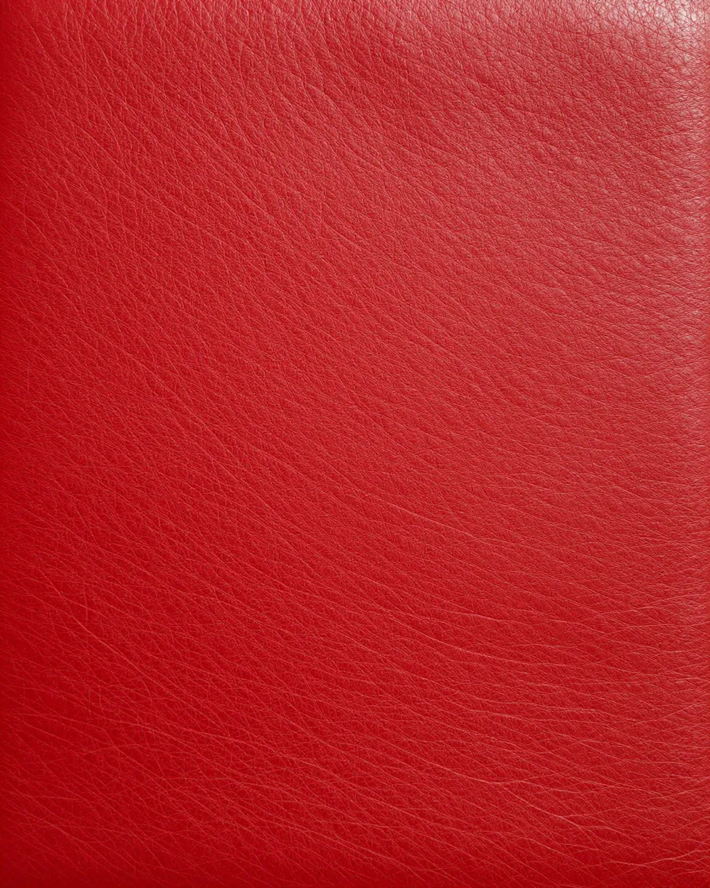 Full frame close-up of smooth deep crimson red leather with fine natural grain and even lighting
