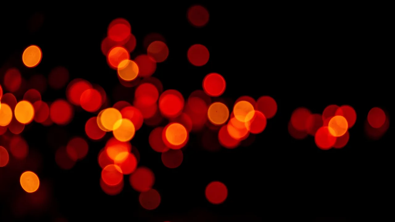 Out-of-focus red and orange circular bokeh light spots scattered across a solid pure black background