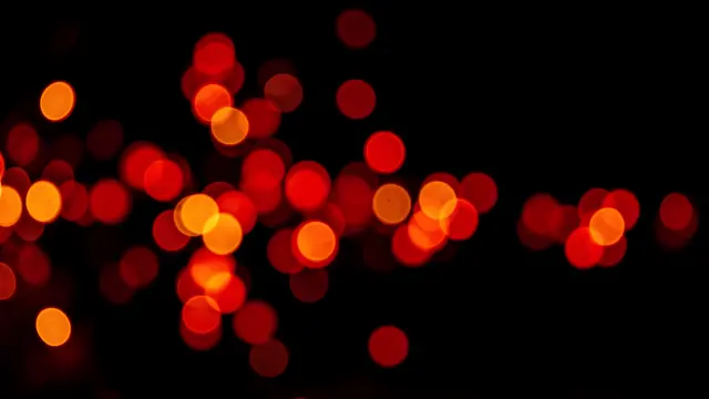 Out-of-focus red and orange circular bokeh light spots scattered across a solid pure black background
