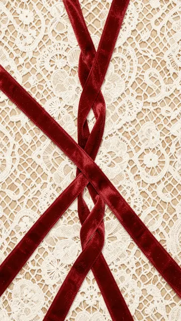 Crisscrossed red velvet ribbons rest over intricate vintage white eyelet lace for a vertical decorative pattern