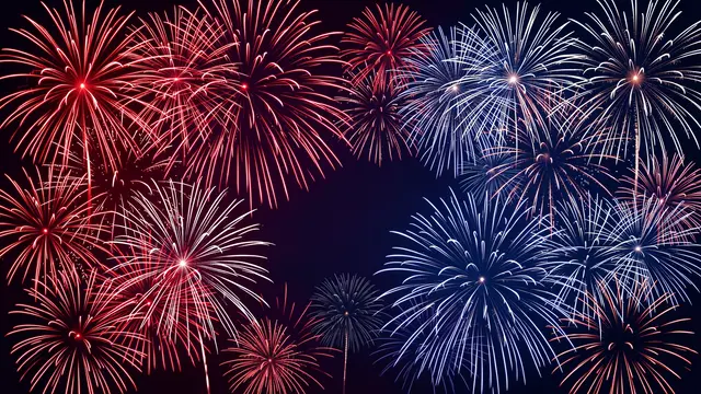 Symmetrical red, white, and blue fireworks burst against a dark night sky with central blank copy space