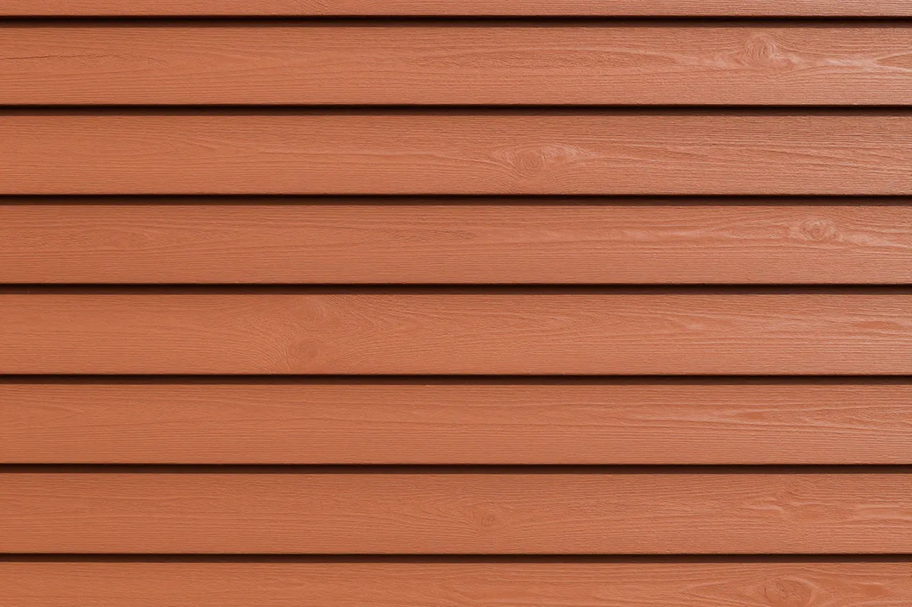 Full frame close-up of horizontal reddish-brown cedar clapboard siding with crisp shadow gaps between planks