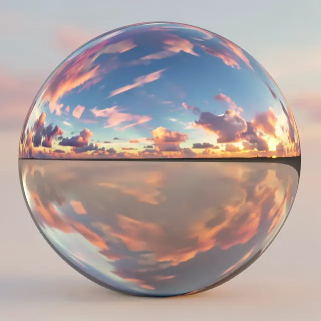 A smooth chrome reflective sphere displays a mirrored colorful sunset sky on a plain neutral surface