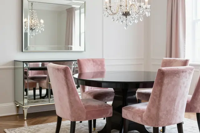 Elegant regency style dining room with pink velvet chairs, glossy black table and crystal chandelier.