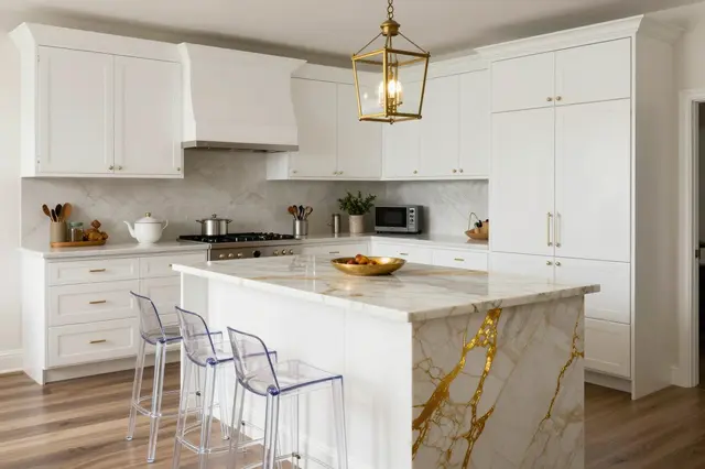 Bright regency glam kitchen with white cabinets, gold veined marble island, acrylic stools and brass pendant light