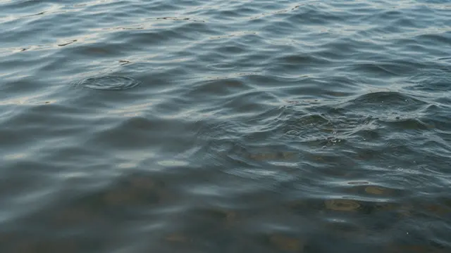 Calm shallow water surface with soft ripples, small splashes, and faint underwater caustic patterns