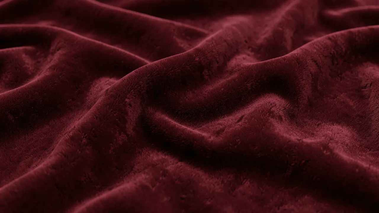 Close-up of soft burgundy velvet fabric arranged in gentle wave-like folds