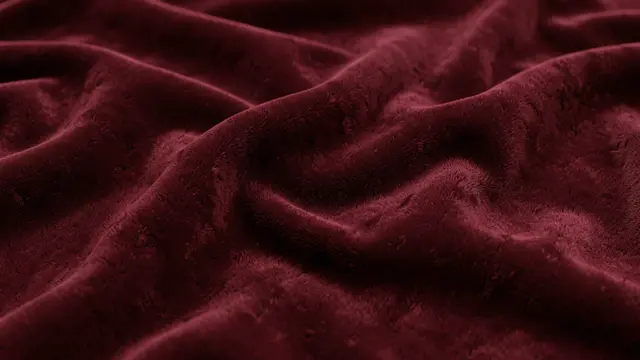 Close-up of soft burgundy velvet fabric arranged in gentle wave-like folds