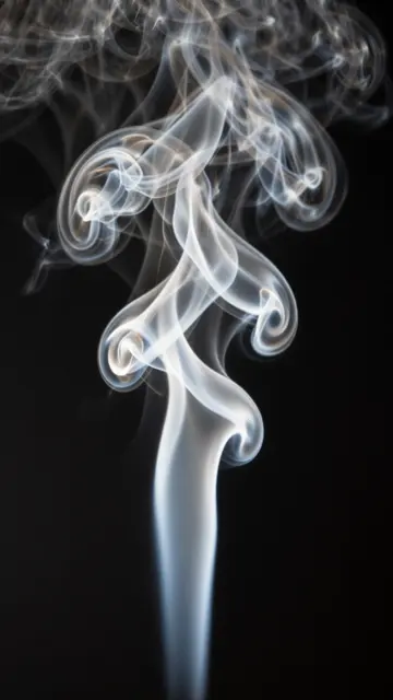 Backlit swirling white smoke rises in delicate folded silky layers against a solid black background