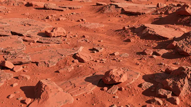 Reddish dusty martian ground scattered with flat and jagged red rocks under bright side lighting