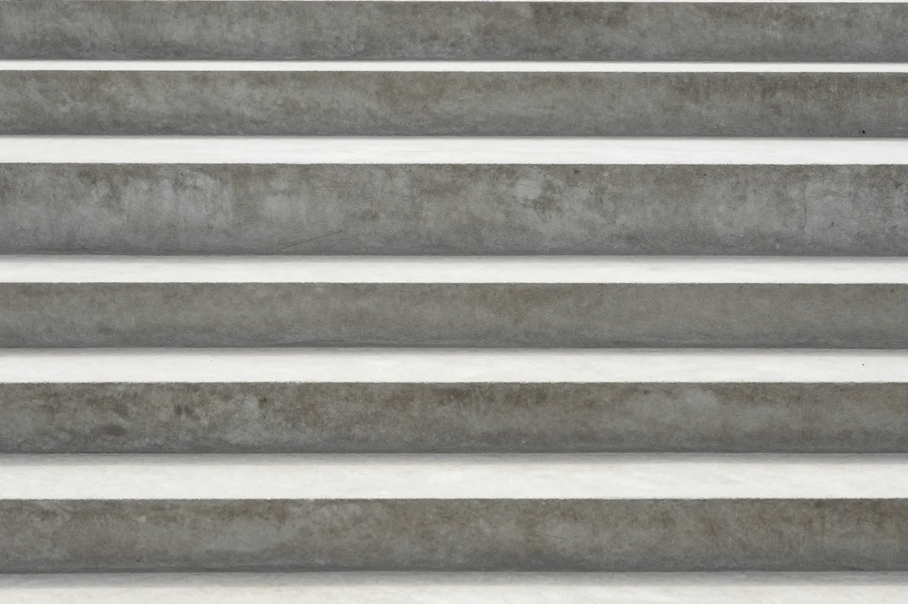 Horizontal rough gray concrete steps with soft parallel shadow lines between each tread