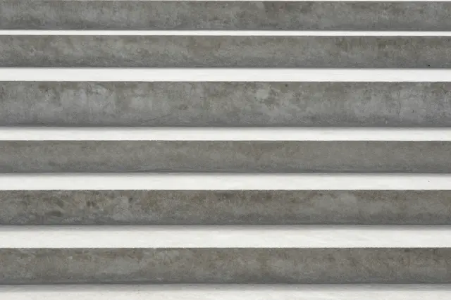 Horizontal rough gray concrete steps with soft parallel shadow lines between each tread